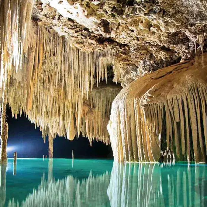 Rio Secreto cave beauty: Stunning view of numerous stalactites hanging over the clear turquoise water in Rio Secreto