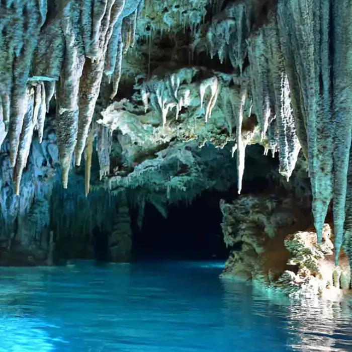 Rio Secreto stalactites: Clear turquoise water reflecting intricate stalactite formations in a cave