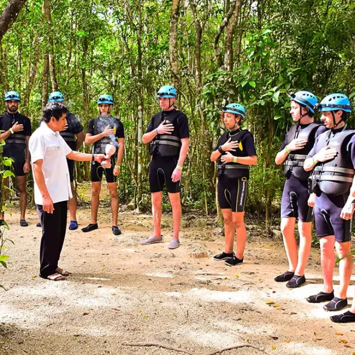 Rio Secreto briefing: Tour guide addressing a group of people in wetsuits and helmets in a lush jungle setting
