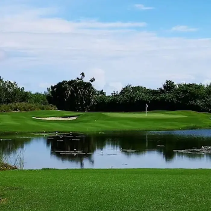 A scenic view of a Jack Nicklaus signature green protected by white sand bunkers and a tranquil lake filled with lily pads