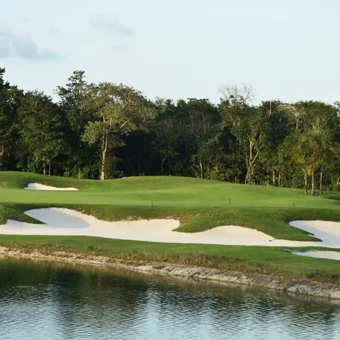 A beautifully shaped golf hole at the Jack Nicklaus Signature course, featuring strategic sand bunkers integrated seamlessly into the natural landscape and bordered by a large lake
