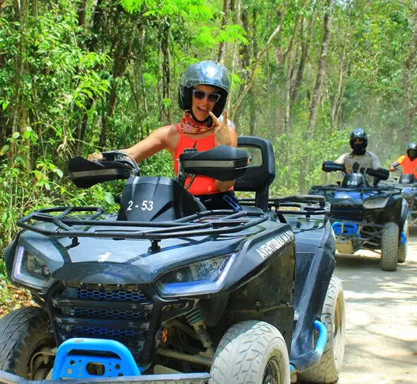 Tourist riding an ATV on a jungle trail, surrounded by lush tropical vegetation