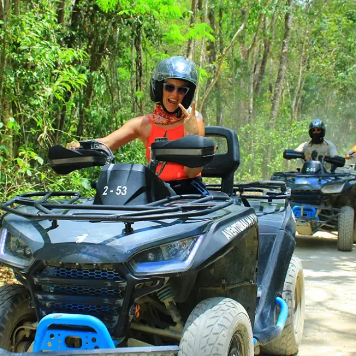 Tourist riding an ATV on a jungle trail, surrounded by lush tropical vegetation