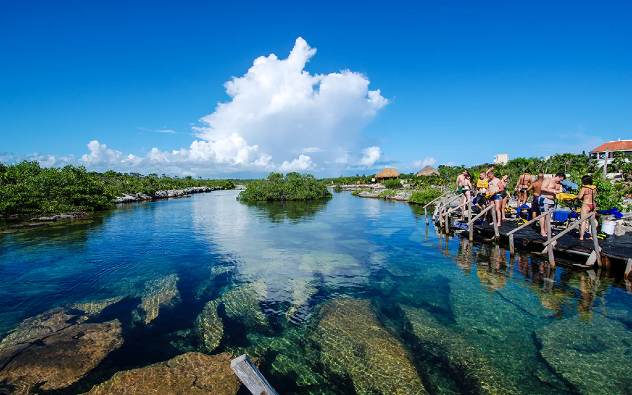 View of a transparent lagoon reflecting the sky with tourists in the background