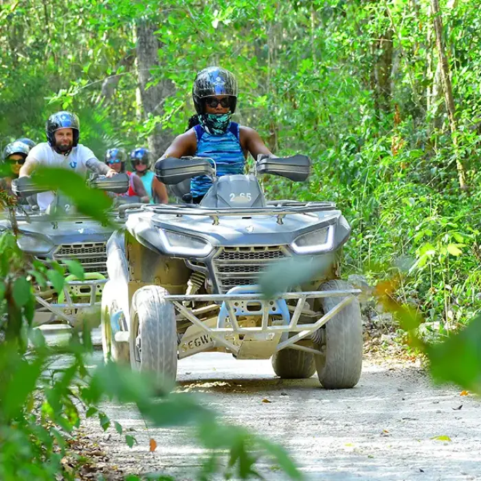 Adventure group riding white ATVs along a dirt road in the jungle