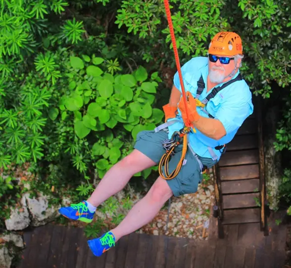 man ziplining over a jungle canopy, smiling during an adventure activity