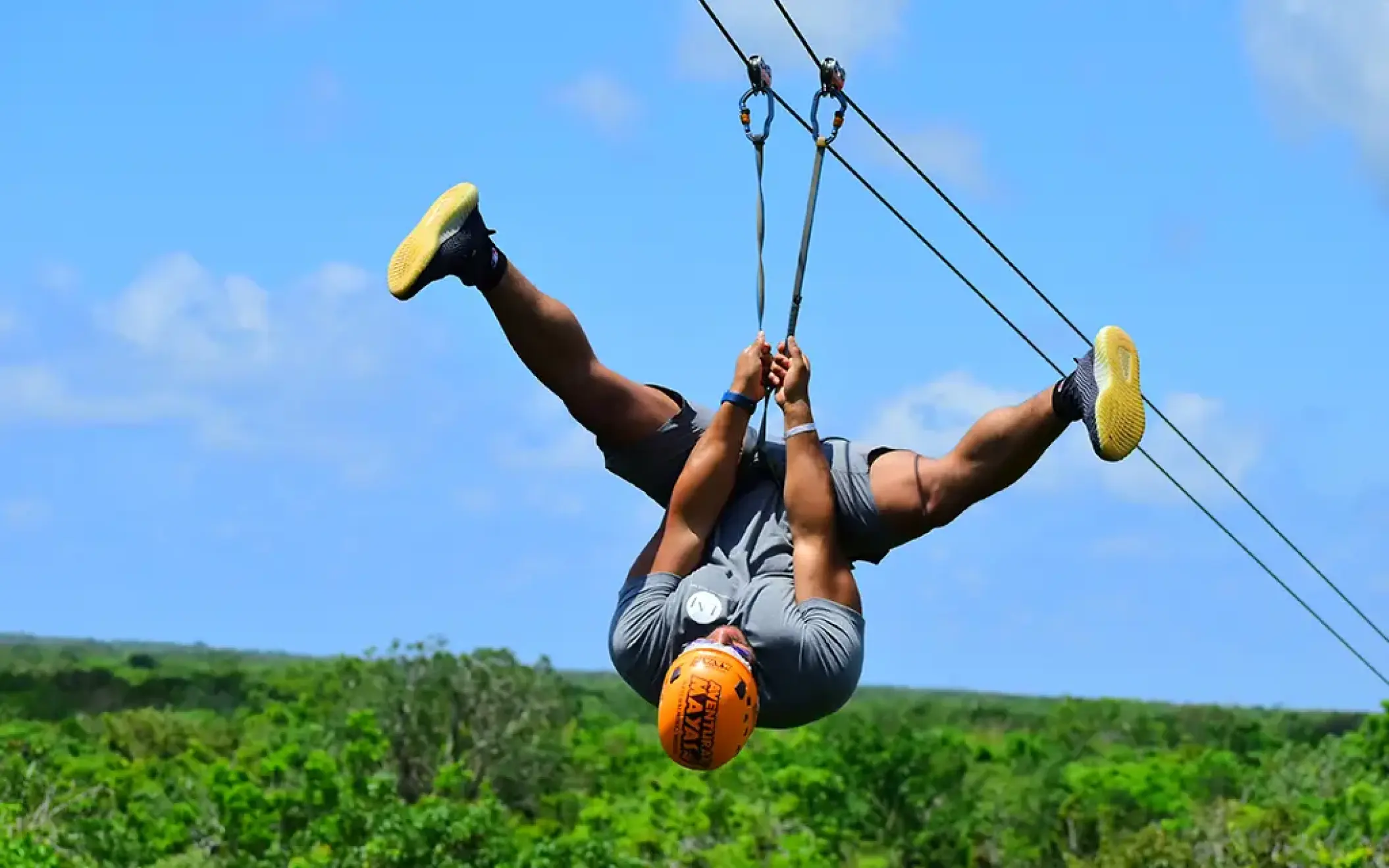 Tourist upside down ziplining above the jungle with a blue sky background