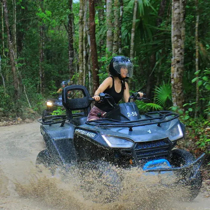 Woman riding an ATV through a splash of water on an adventurous jungle ride
