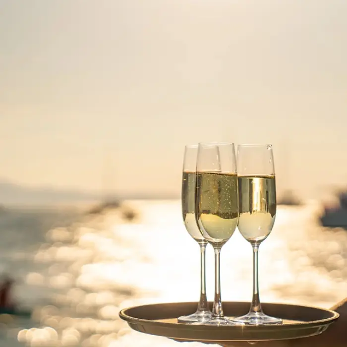 Server holding a tray with two glasses of champagne on a sunset sail in Playa del Carmen