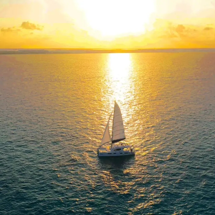 Sailboat sailing on the calm ocean during a vibrant sunset in Playa del Carmen