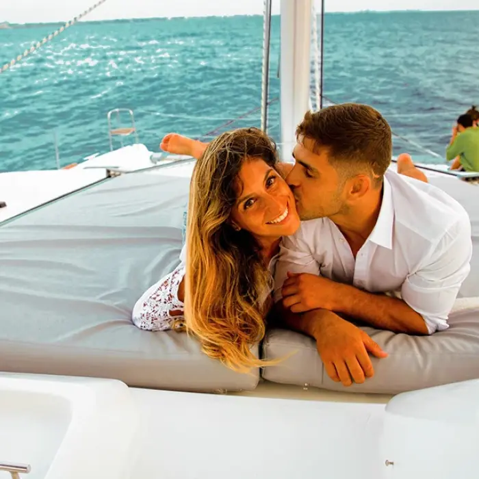 Couple relaxing and embracing on the deck of a sailboat at sunset in Playa del Carmen. Romantic cruise
