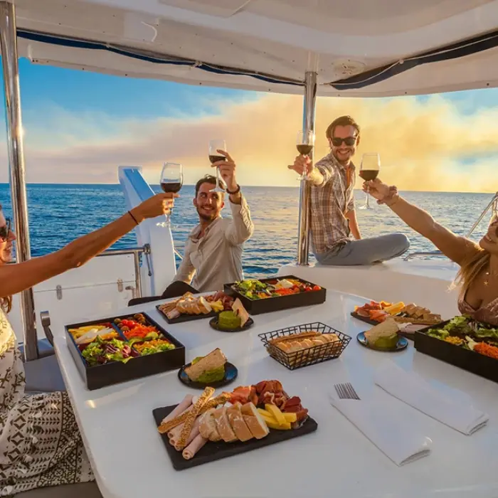Group of friends toasting with drinks on a sunset sail in Playa del Carmen. Cheers to the sunset
