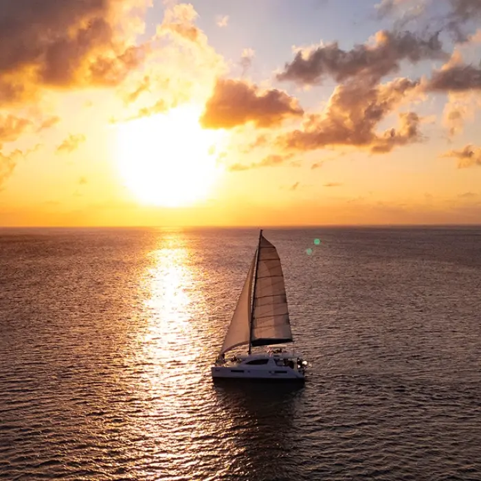 Sailboat silhouetted against a vibrant sunset in Playa del Carmen. Romantic evening cruise