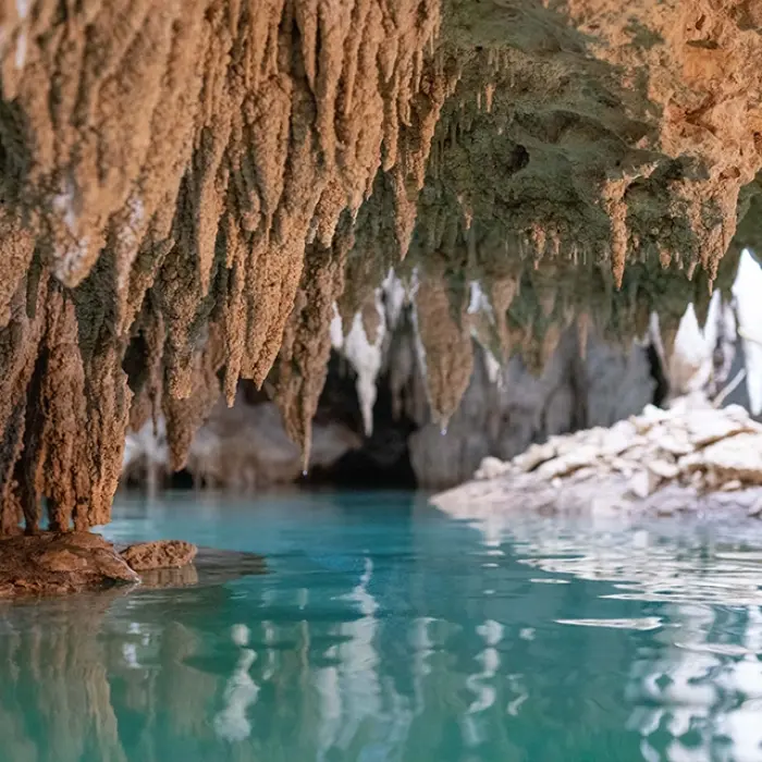 A beautiful underground cenote with rock formations and turquoise water