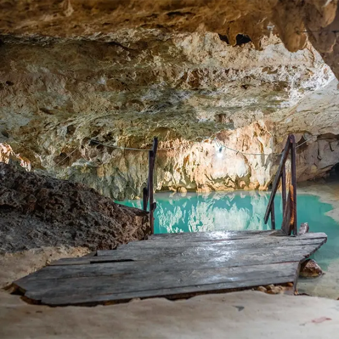 A hidden cenote inside a cave with wooden stairs leading to the water