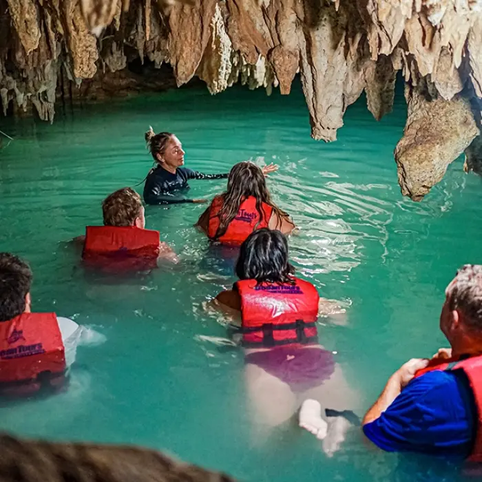 Tourists exploring a cenote inside a cave with clear blue water