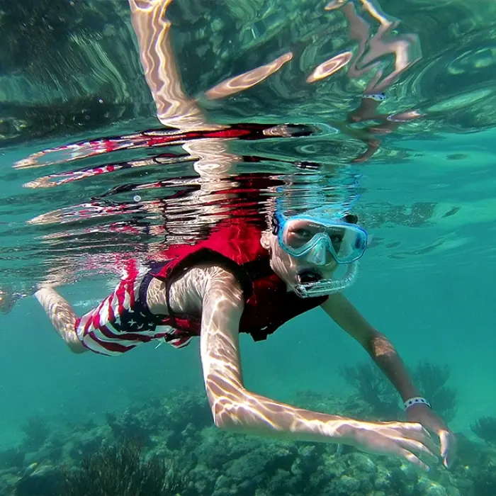Snorkeler swimming underwater in a tropical sea, wearing a mask and life jacket