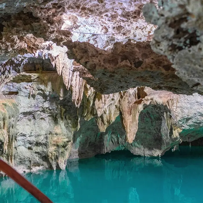 Close-up view of cave formations inside a cenote with turquoise water