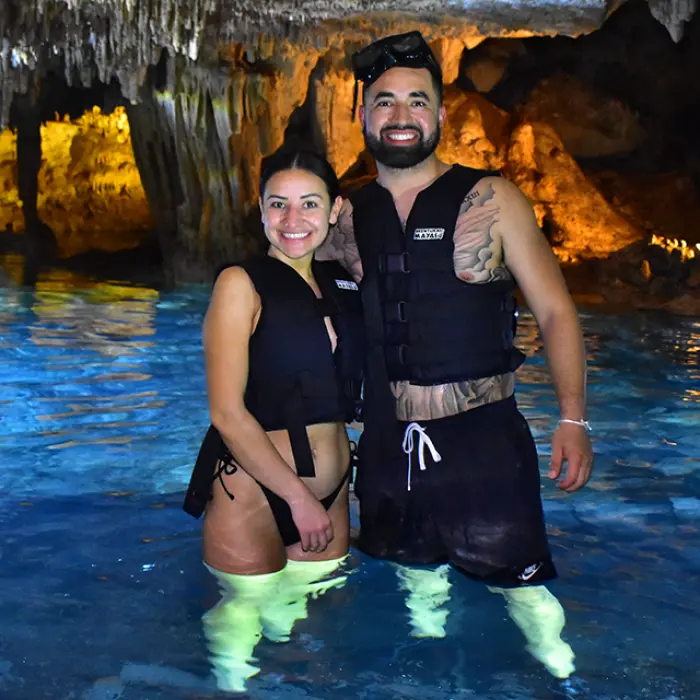 Couple smiling and enjoying a refreshing swim in a mystical cenote during their Tulum adventure