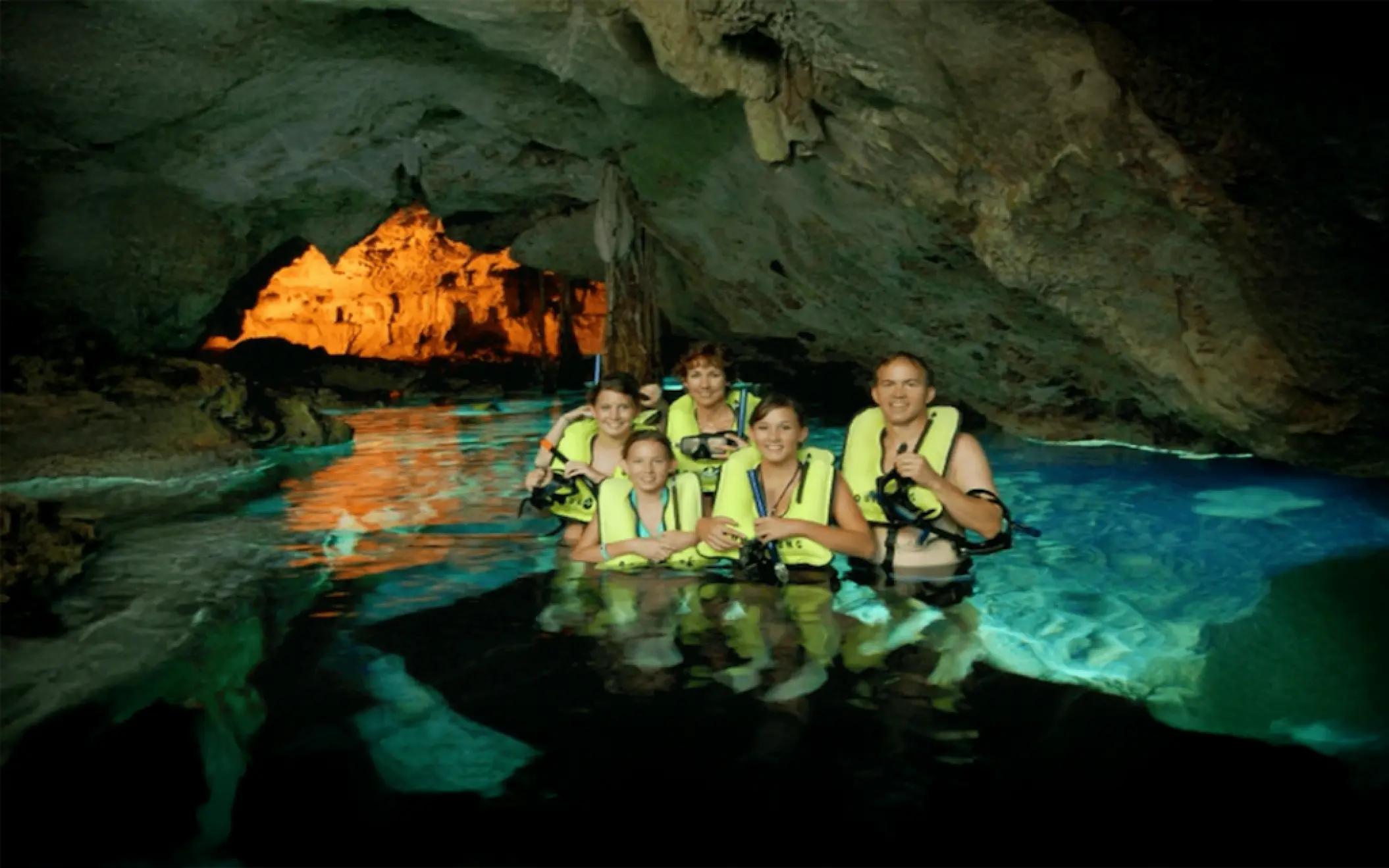 Family adventure inside a peaceful cenote cave, wearing life jackets and enjoying the beauty of nature