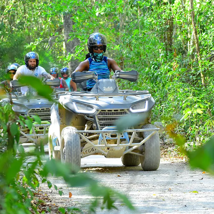 A group of friends driving ATVs through the lush jungle trails of Tulum