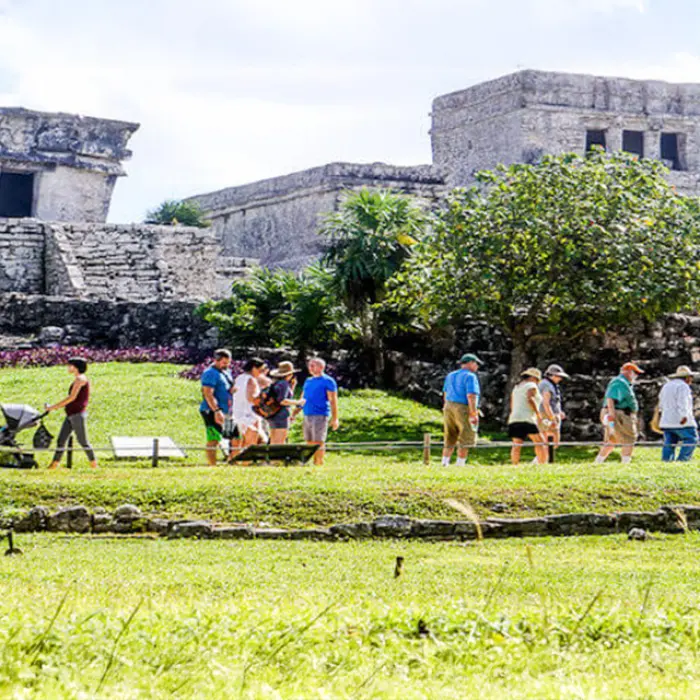 Tourists exploring the ancient Mayan city of Tulum with a knowledgeable guide under the sun