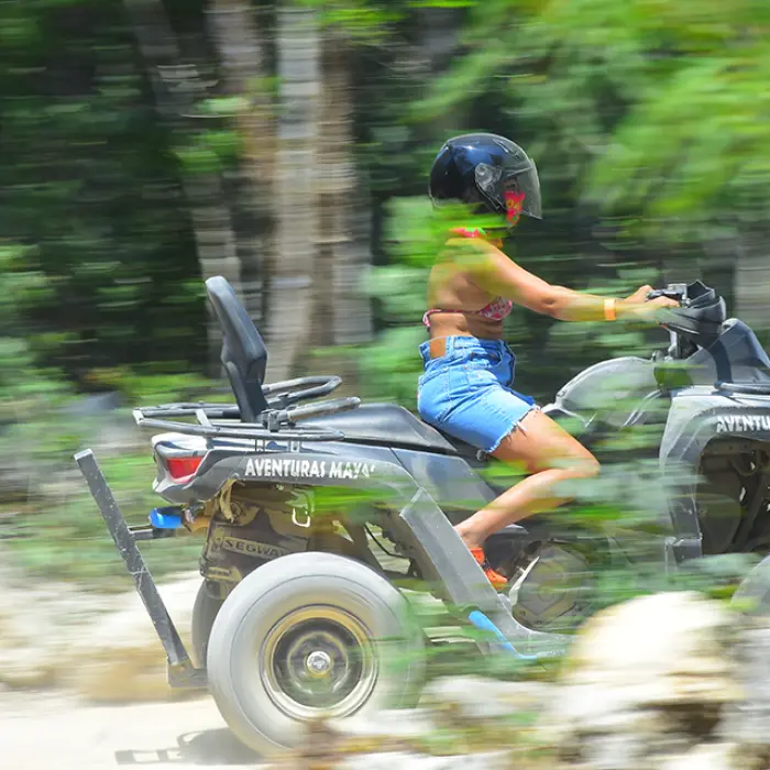 Woman riding an ATV with confidence through the dense and exciting jungle terrain of Tulum