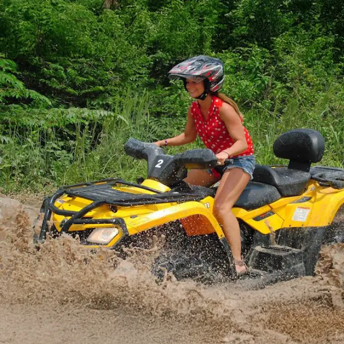 Woman getting the full thrill as she kicks up mud on her ATV during a wild ride in Tulum