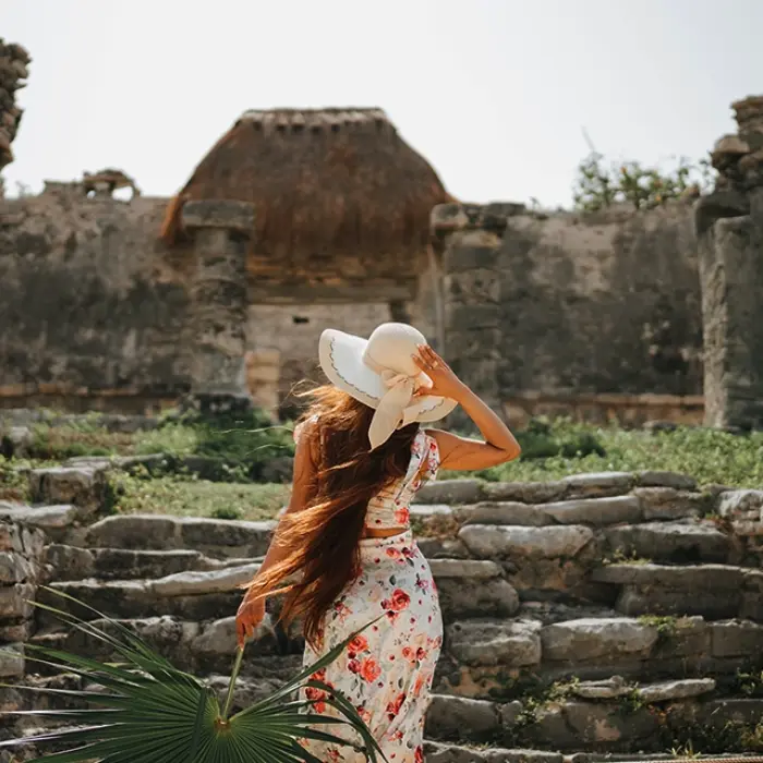 Woman in a sunhat exploring the ancient stone steps of the Tulum archaeological site