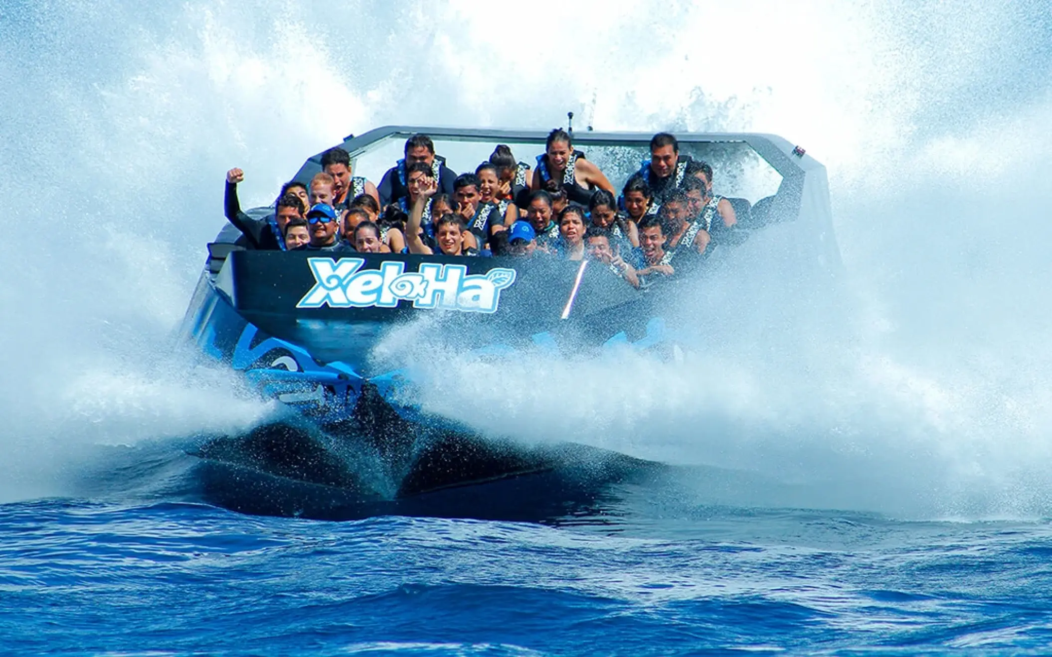 Group speeding over water on the Xel-Há jet boat ride, splashing through waves