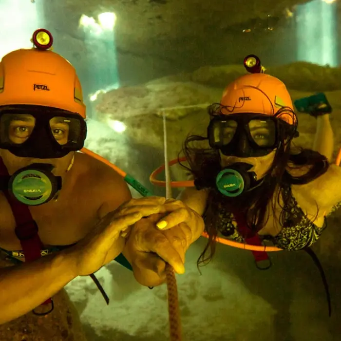 Couple doing Sea Trek underwater walk wearing special helmets inside a cenote