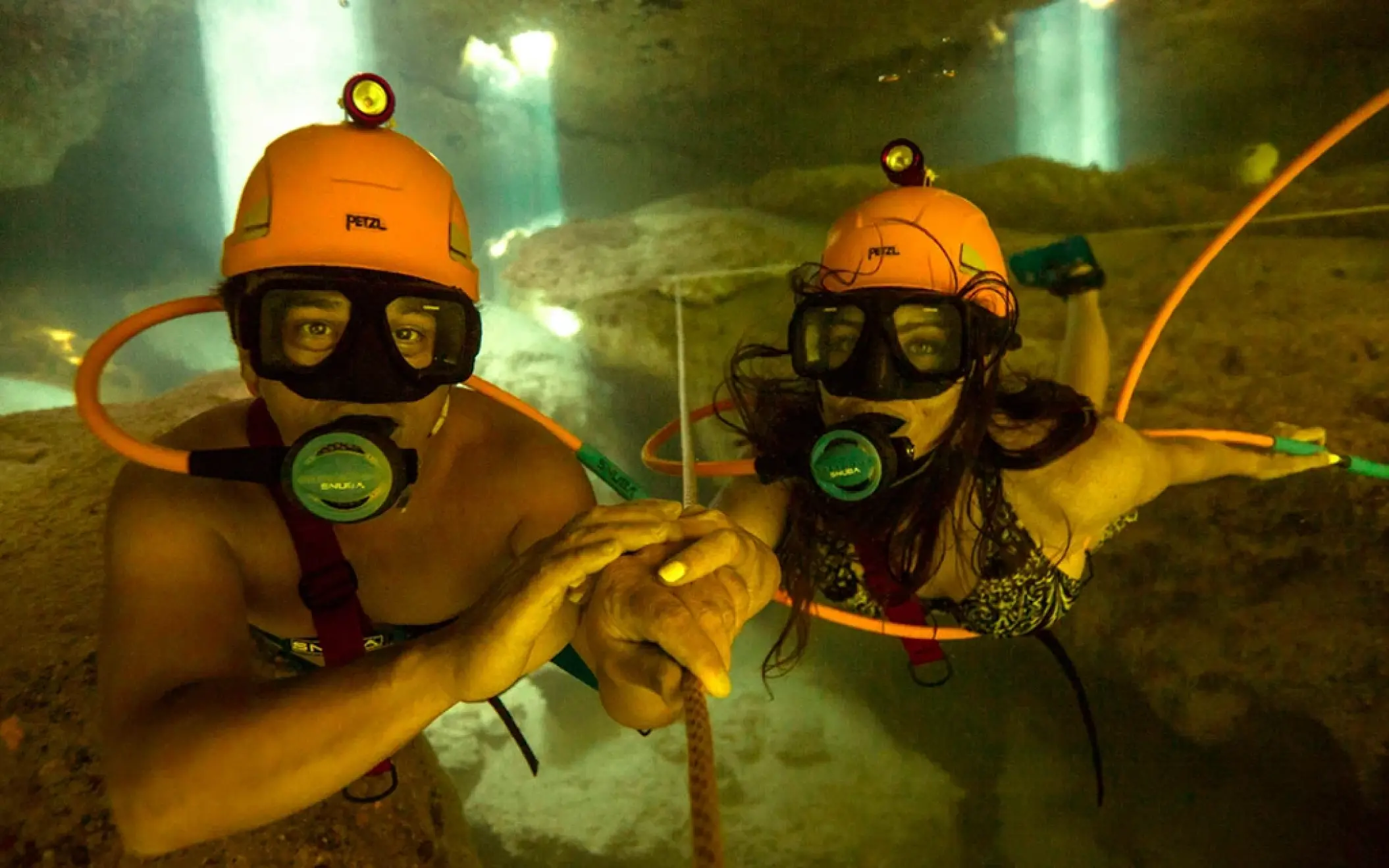 Couple doing Sea Trek underwater walk wearing special helmets inside a cenote