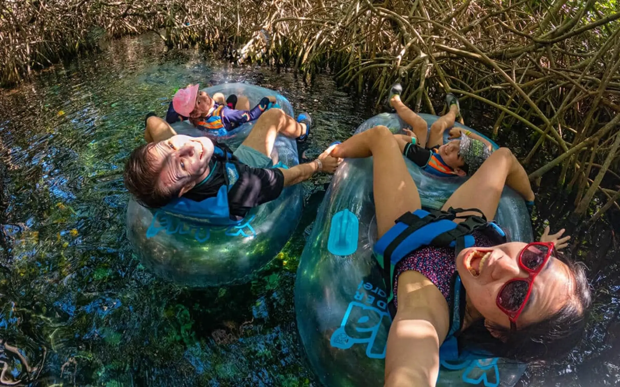 Friends relaxing in inner tubes while floating through mangroves in the lazy river