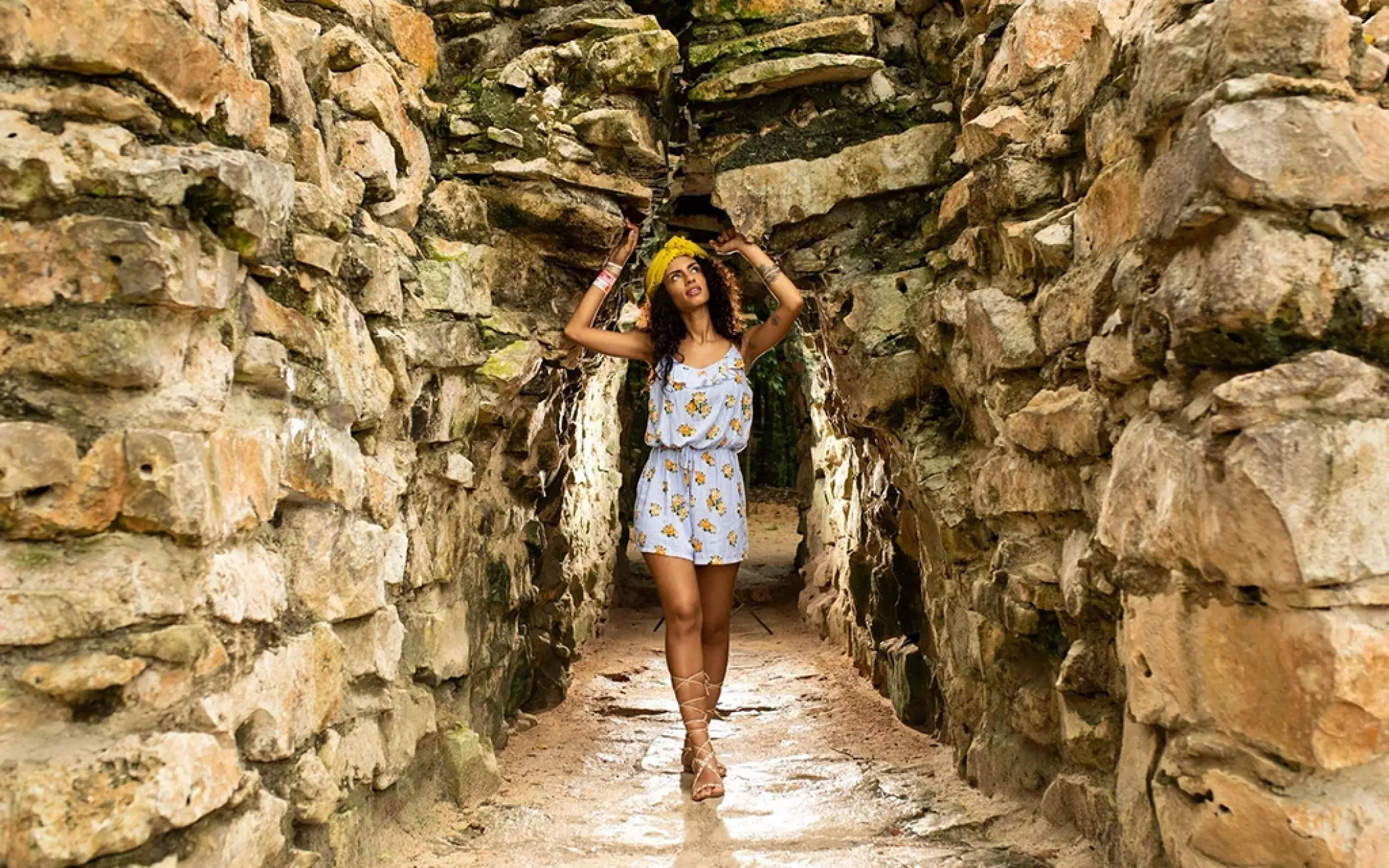 Tourist walking through a narrow, ancient stone tunnel at the Tulum ruins