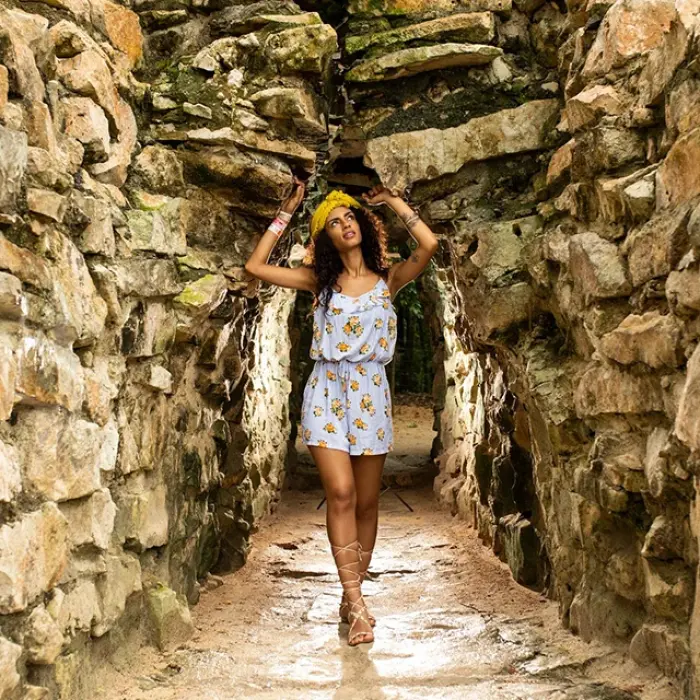 Tourist walking through a narrow, ancient stone tunnel at the Tulum ruins