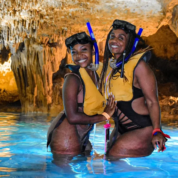 Two women posing happily in a glowing cenote after snorkeling in Xel-Há. Filename: women-snorkeling-xelha-cenote