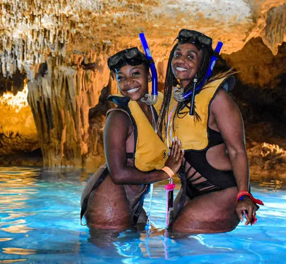 Two women posing happily in a glowing cenote after snorkeling in Xel-Há. Filename: women-snorkeling-xelha-cenote