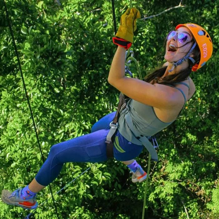 Woman zip-lining over the jungle and water during an adventure activity at Xel-Há