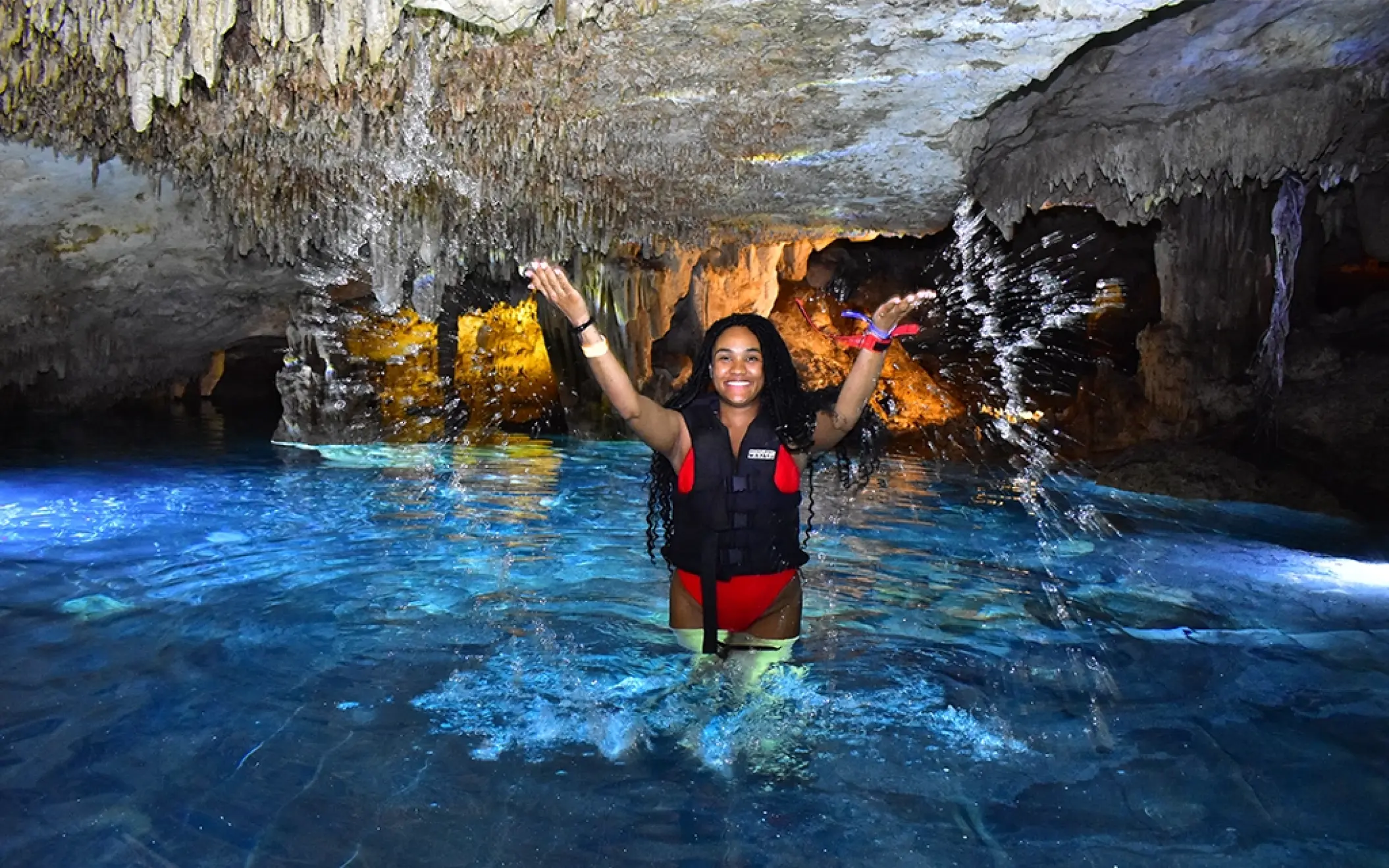 Person swimming in a cenote with natural rock formations during the Tulum Xtreme Tour