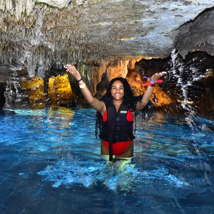Person swimming in a cenote with natural rock formations during the Tulum Xtreme Tour