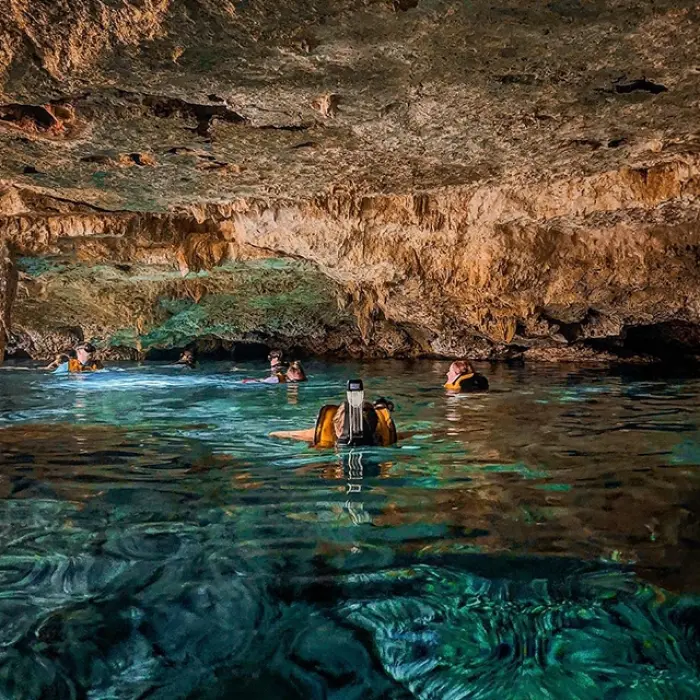 Wide-angle shot of a natural underground cenote with rock formations, included in the Tulum Xtreme Tour