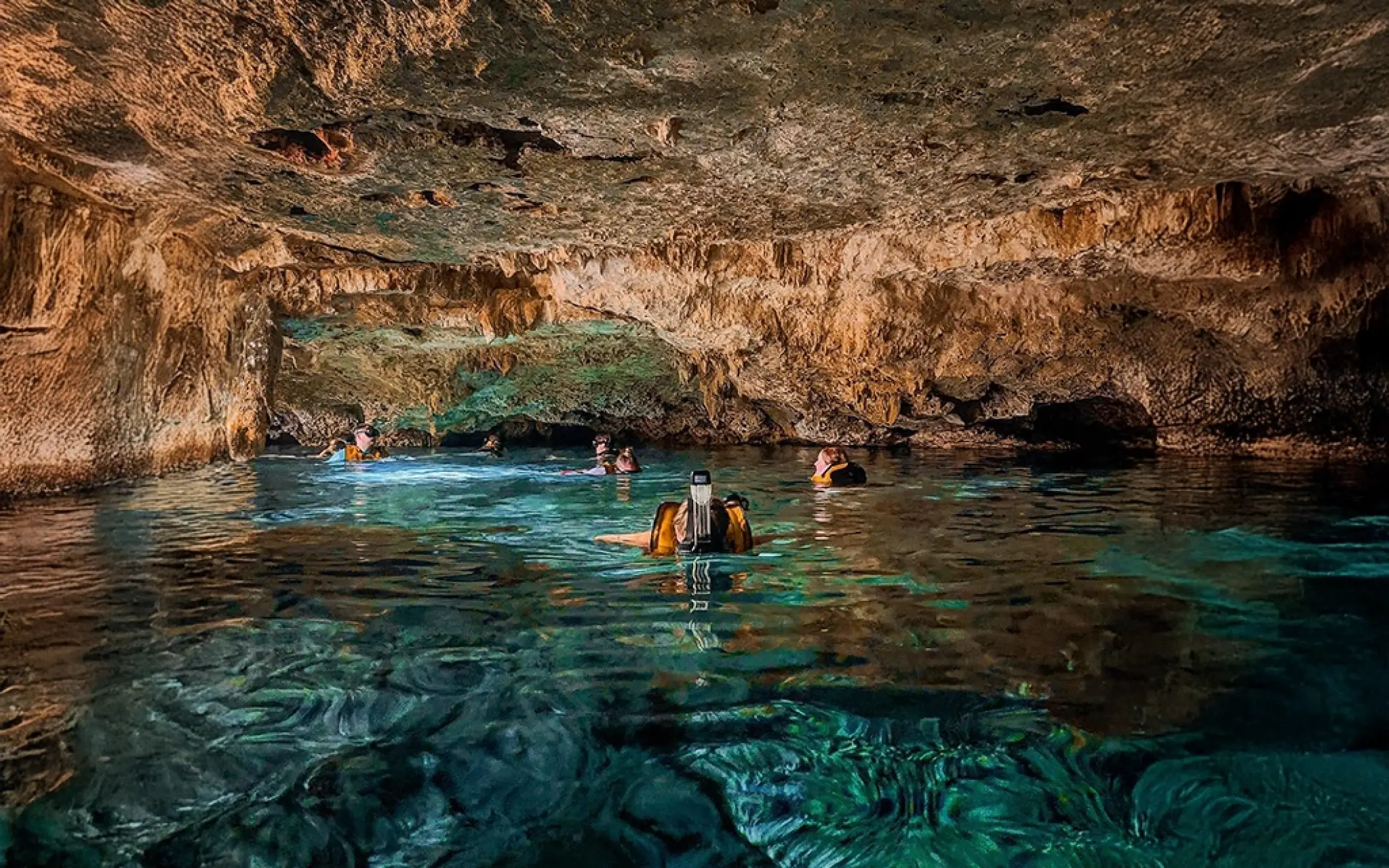 Wide-angle shot of a natural underground cenote with rock formations, included in the Tulum Xtreme Tour