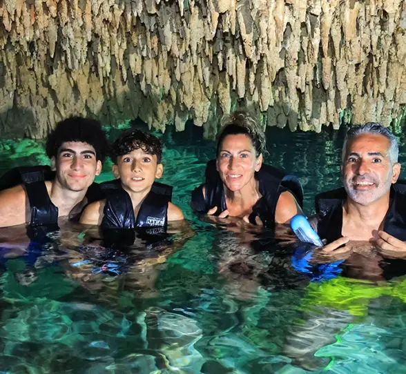 Group of people enjoying a swim in a cenote surrounded by natural rock walls, included in the Tulum Xtreme Tour