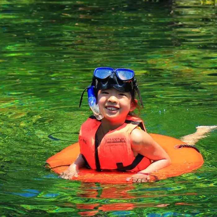 Young child swimming in a natural cenote with clear water, part of the Tulum Xtreme Tour