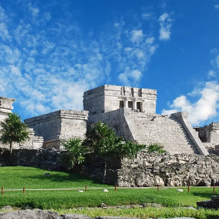 Stone ruins of an ancient Mayan temple with the ocean in the background, part of the Tulum Xtreme Tour