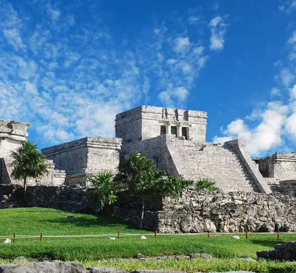 Stone ruins of an ancient Mayan temple with the ocean in the background, part of the Tulum Xtreme Tour