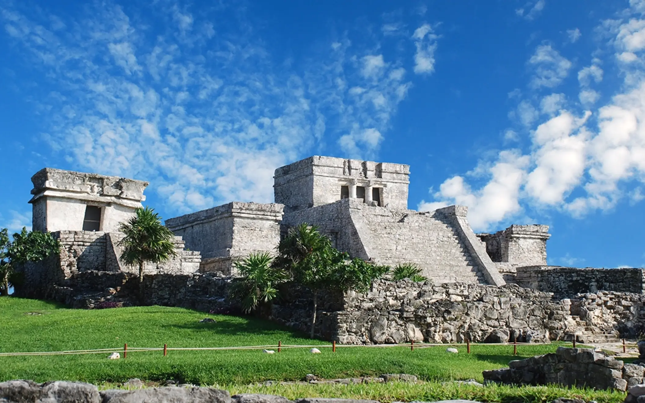 Stone ruins of an ancient Mayan temple with the ocean in the background, part of the Tulum Xtreme Tour