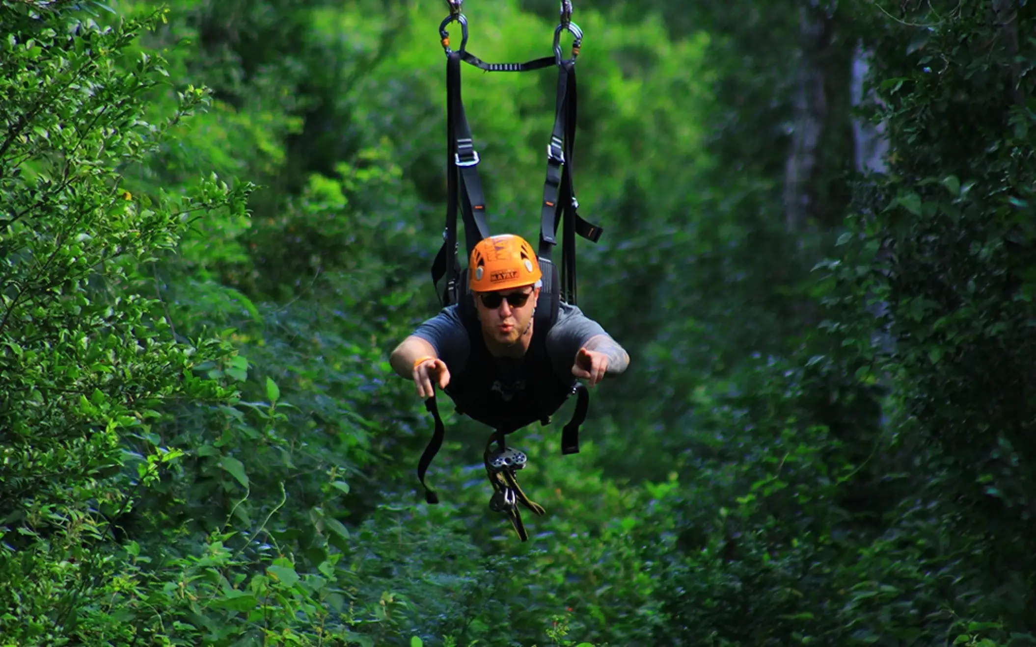Close-up of a person gripping a zipline cable, soaring over the jungle on the Tulum Xtreme Tour