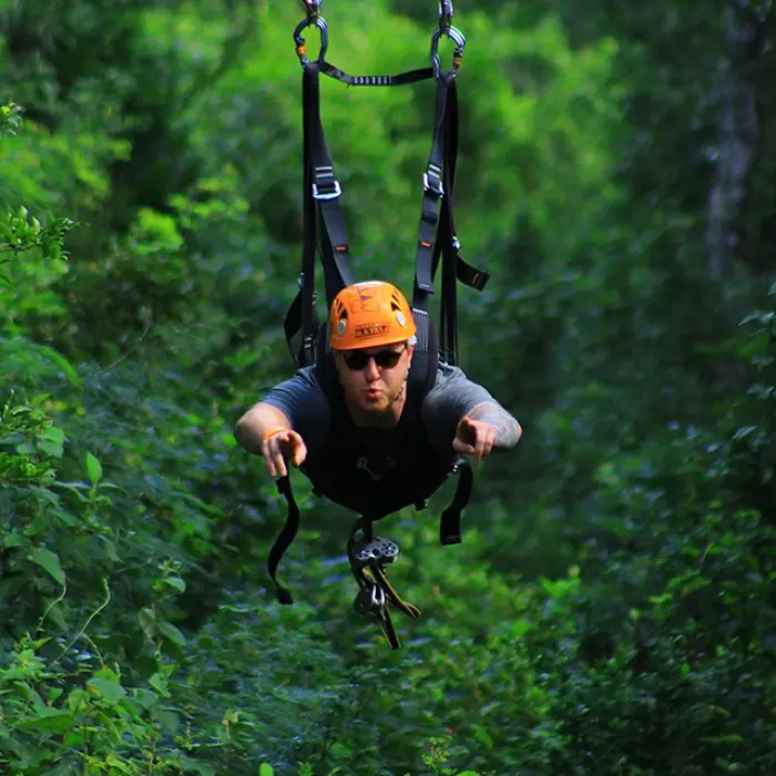 Close-up of a person gripping a zipline cable, soaring over the jungle on the Tulum Xtreme Tour