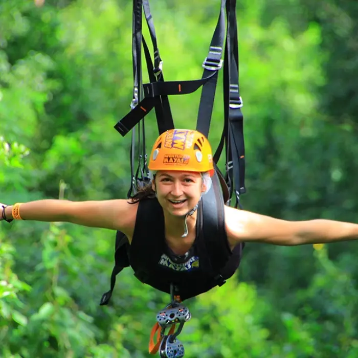 Person riding a zipline high above the jungle canopy as part of the Tulum Xtreme Tour